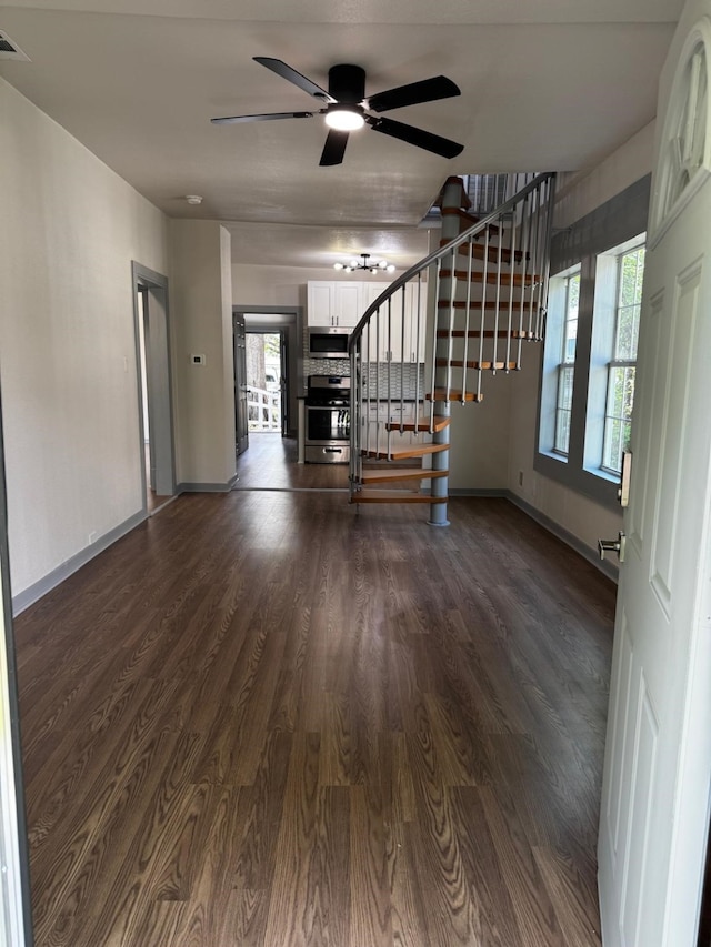 3401 Illinois St, Baytown, TX 77520 - unfurnished living room featuring a healthy amount of sunlight, baseboards, a ceiling fan, stairs, and dark wood-type flooring