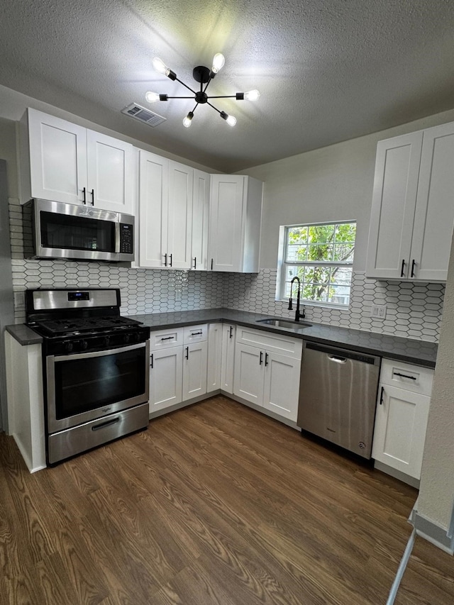 3401 Illinois St, Baytown, TX 77520 - kitchen featuring dark wood-style floors, a sink, dark countertops, visible vents, and appliances with stainless steel finishes