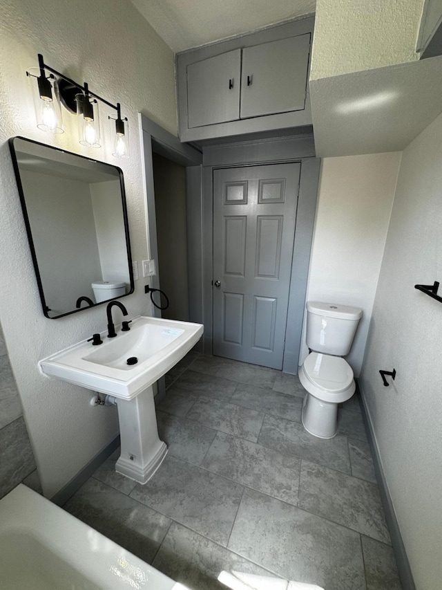 3401 Illinois St, Baytown, TX 77520 - bathroom featuring a textured wall, toilet, and baseboards