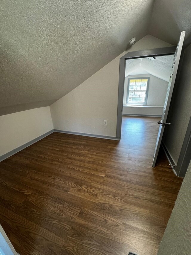 3401 Illinois St, Baytown, TX 77520 - additional living space featuring a textured ceiling, vaulted ceiling, and dark wood-style flooring