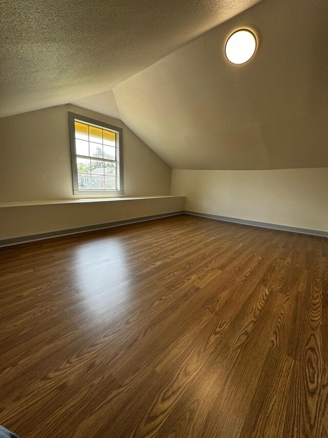 3401 Illinois St, Baytown, TX 77520 - additional living space featuring vaulted ceiling, dark wood-style flooring, and a textured ceiling