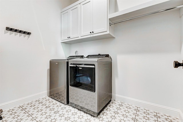 laundry room featuring baseboards, light floors, cabinet space, and washing machine and clothes dryer