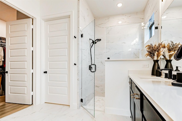 bathroom featuring vanity, marble finish floor, a marble finish shower, and a spacious closet