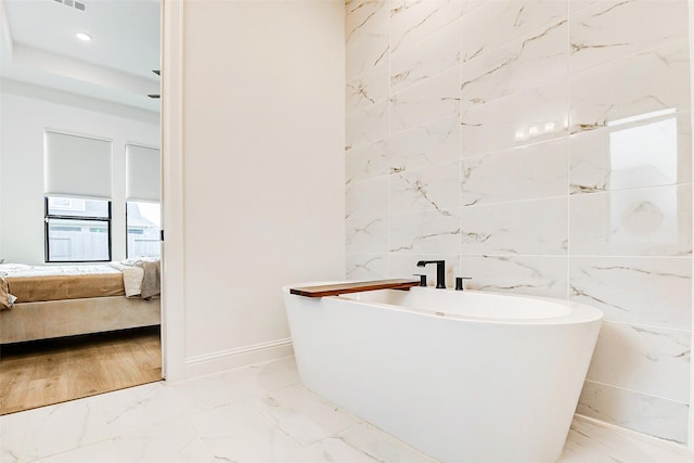 ensuite bathroom with baseboards, marble finish floor, ensuite bath, and a soaking tub