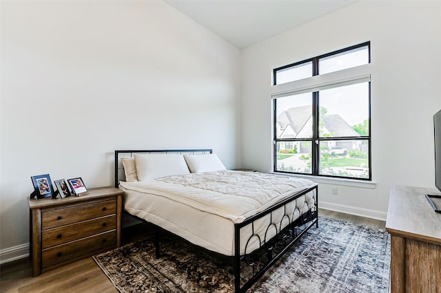 bedroom featuring baseboards, vaulted ceiling, and wood finished floors