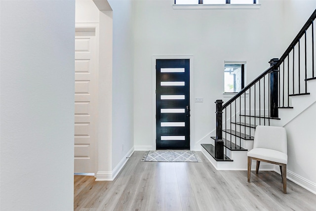 entryway featuring baseboards, wood finished floors, stairway, and a towering ceiling