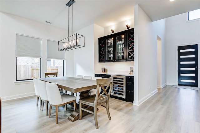dining area featuring wine cooler, visible vents, bar area, and light wood-style floors