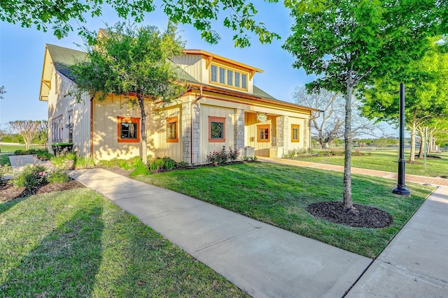 view of front facade with board and batten siding, a front lawn, and stone siding