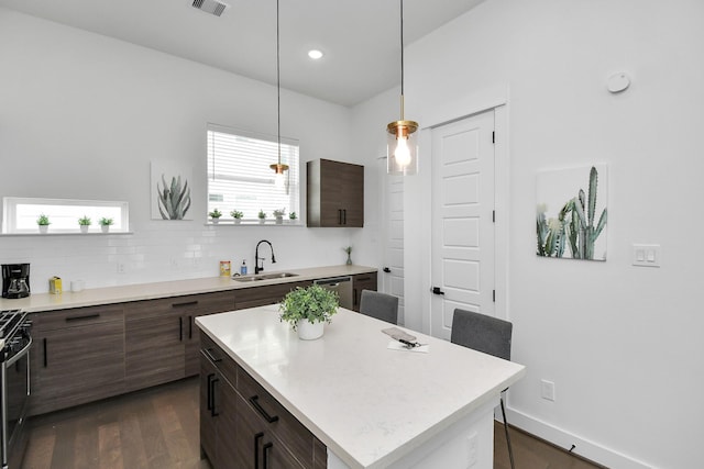 kitchen with light countertops, backsplash, visible vents, a sink, and dark wood-type flooring