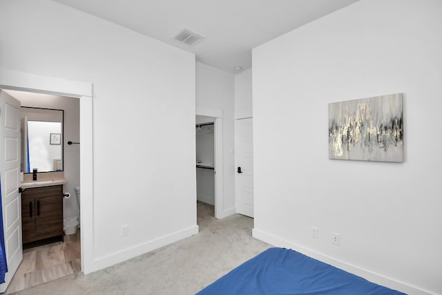 unfurnished bedroom featuring a sink, baseboards, a spacious closet, visible vents, and carpet