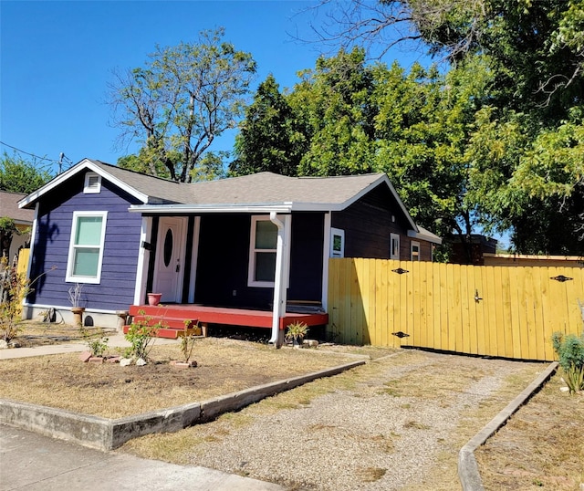 view of front facade with fence, a shingled roof, covered porch, and a gate