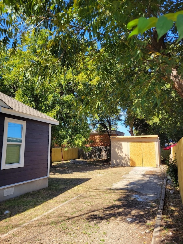 view of yard featuring a storage unit, an outdoor structure, and a fenced backyard