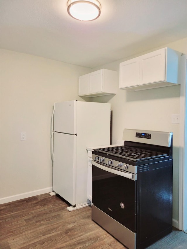 151 Canton, San Antonio, TX 78202 - kitchen with stainless steel range with gas stovetop, dark wood-type flooring, freestanding refrigerator, white cabinets, and baseboards