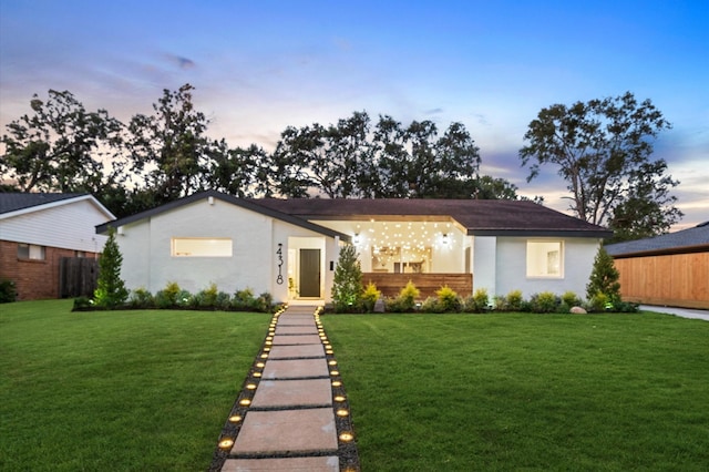 ranch-style house featuring a lawn and stucco siding