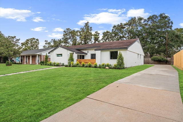 single story home with brick siding, a front yard, concrete driveway, and fence