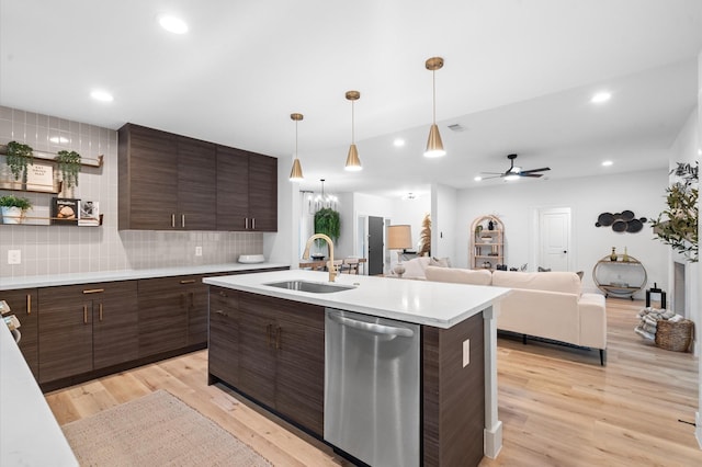 kitchen with stainless steel dishwasher, light countertops, a sink, and light wood-style flooring