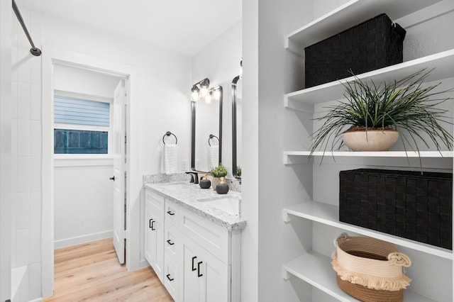 full bathroom with walk in shower, wood finished floors, double vanity, and a sink