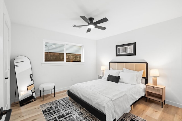 bedroom with light wood finished floors, baseboards, and ceiling fan