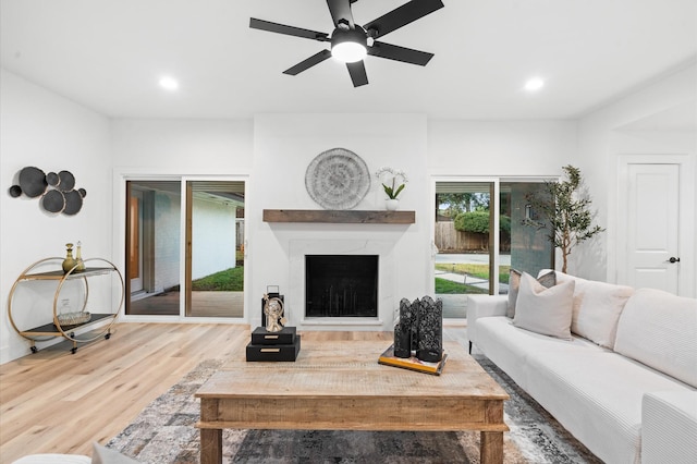 living room featuring a ceiling fan, wood finished floors, recessed lighting, and a fireplace