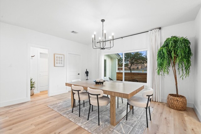 dining area featuring baseboards, a chandelier, visible vents, and light wood-style floors