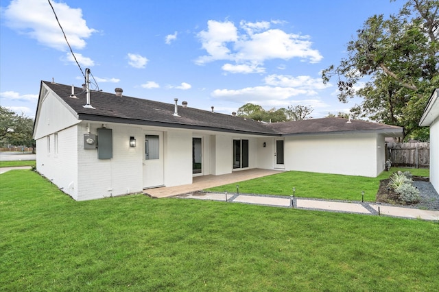 rear view of property with fence, a lawn, roof with shingles, and brick siding