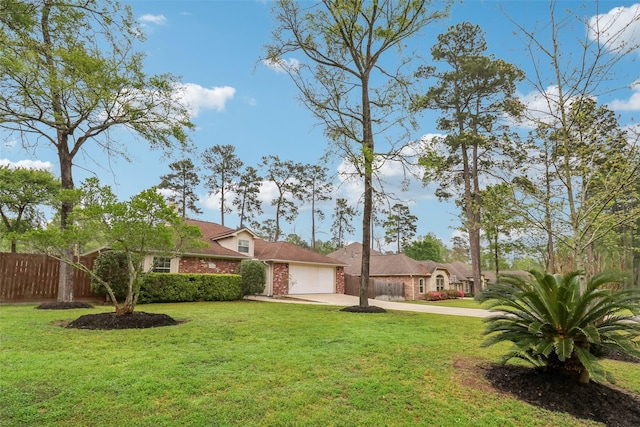 view of front of property with fence, an attached garage, driveway, brick siding, and a front yard