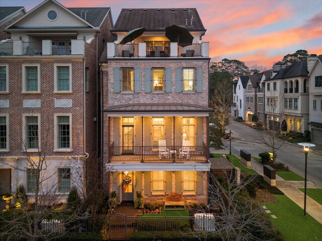 305 Royale Heights Ln, Houston, TX 77024 - back of house at dusk featuring a residential view, a fenced front yard, a gate, brick siding, and a balcony