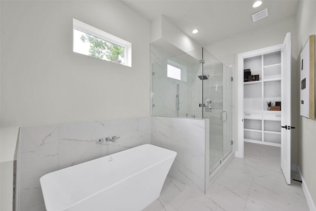 bathroom with a freestanding tub, a marble finish shower, marble finish floor, a walk in closet, and visible vents