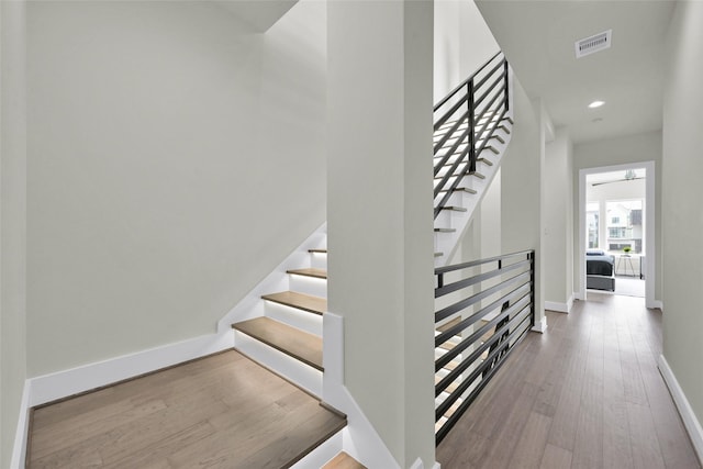 staircase featuring wood finished floors, recessed lighting, visible vents, and baseboards