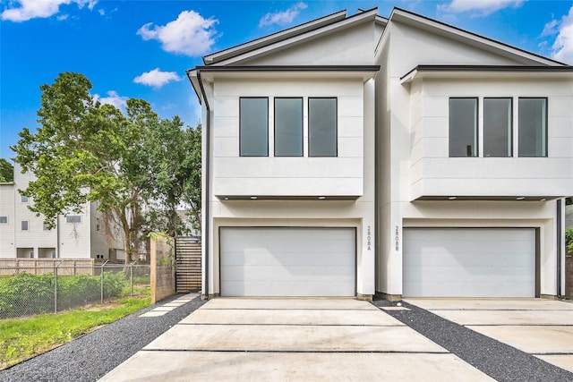 view of front facade with stucco siding, fence, driveway, and a garage