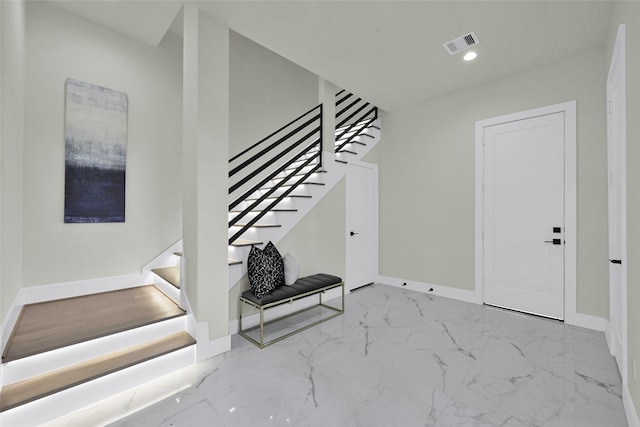 interior space featuring visible vents, baseboards, marble finish floor, and stairs