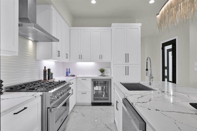 kitchen featuring white cabinetry, a sink, beverage cooler, stainless steel appliances, and wall chimney exhaust hood