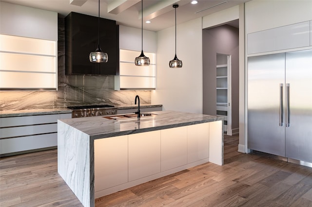2222 Branard St, Houston, TX 77098 - kitchen with dark stone counters, a sink, stainless steel appliances, decorative backsplash, and light wood-type flooring