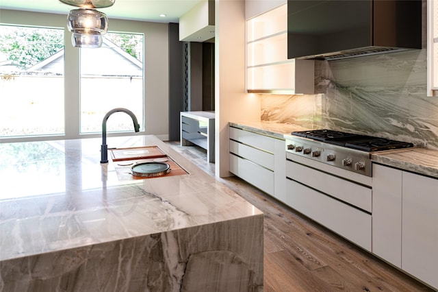2222 Branard St, Houston, TX 77098 - kitchen with modern cabinets, stainless steel gas stovetop, light wood-style floors, backsplash, and wall chimney range hood