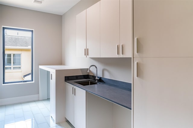 2222 Branard St, Houston, TX 77098 - kitchen with dark countertops, baseboards, white cabinets, and a sink