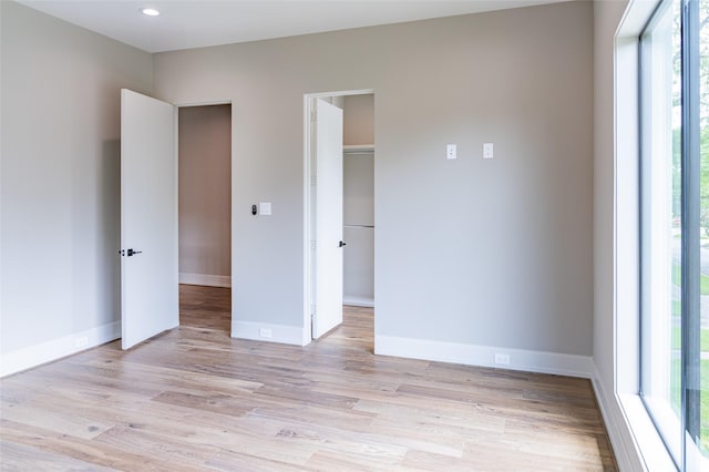 2222 Branard St, Houston, TX 77098 - unfurnished bedroom featuring baseboards, a spacious closet, multiple windows, and light wood finished floors