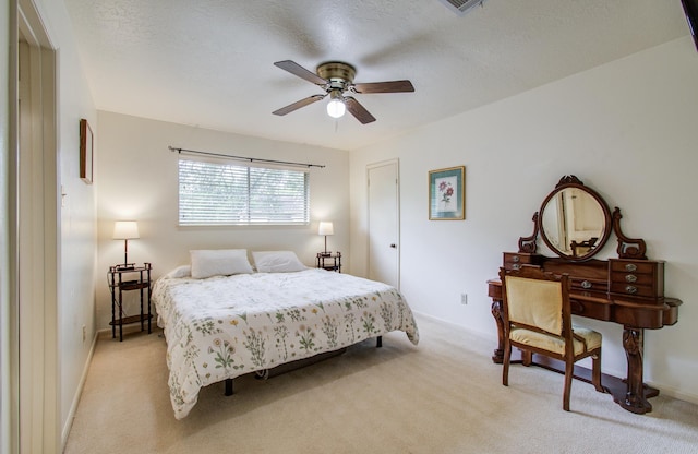 bedroom with a ceiling fan, baseboards, light carpet, and a textured ceiling