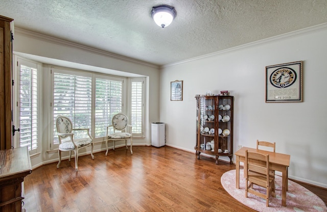 living area with ornamental molding, a textured ceiling, wood finished floors, and a wealth of natural light