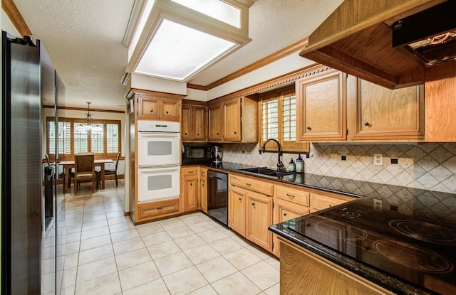 kitchen featuring dark countertops, a sink, cooktop, double oven, and black dishwasher