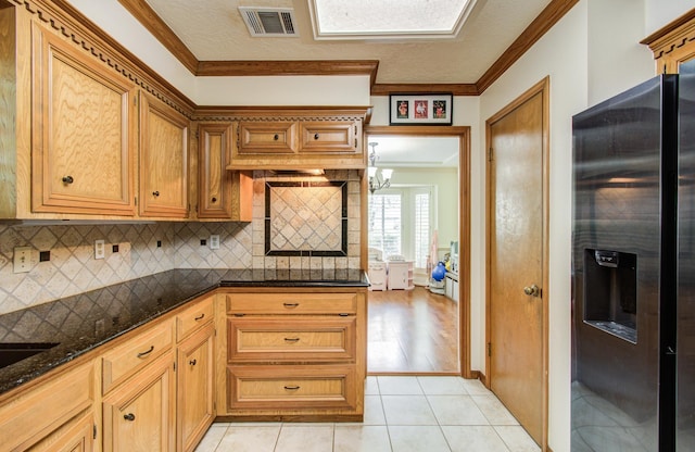 kitchen featuring visible vents, decorative backsplash, crown molding, dark stone counters, and stainless steel fridge with ice dispenser