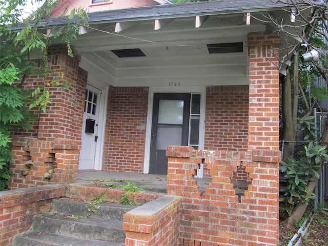 entrance to property featuring brick siding and covered porch
