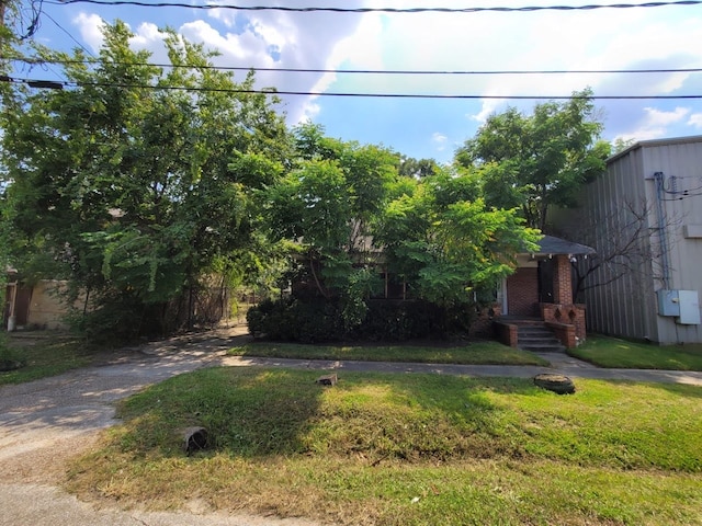 obstructed view of property with a front lawn, brick siding, and driveway