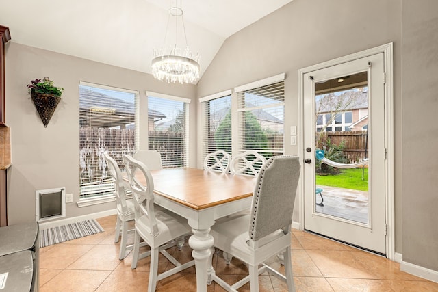 dining area with an inviting chandelier, light tile patterned floors, vaulted ceiling, and baseboards