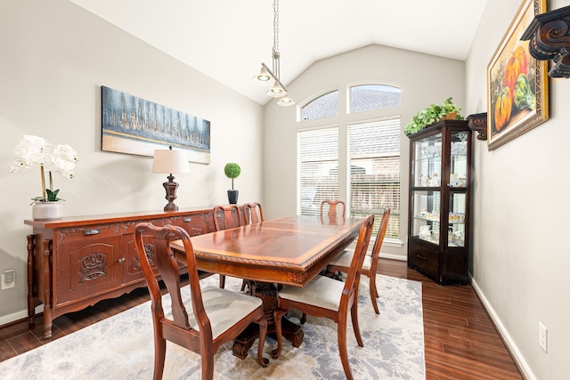 dining area featuring lofted ceiling, dark wood-type flooring, and baseboards