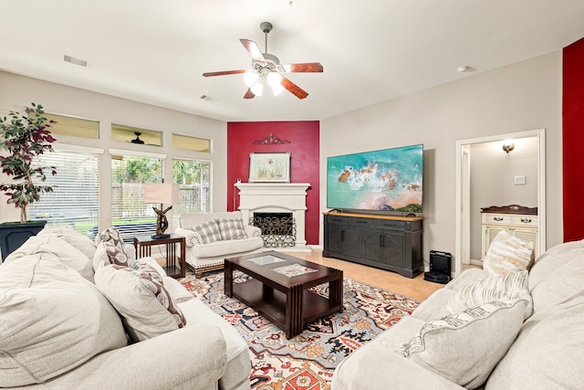 living room with visible vents, ceiling fan, and a fireplace with raised hearth