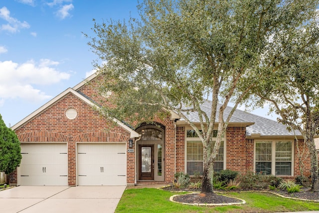 traditional-style home featuring brick siding, roof with shingles, a front lawn, concrete driveway, and an attached garage
