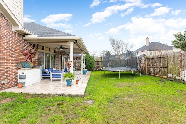 view of yard with a trampoline, a patio area, a fenced backyard, outdoor lounge area, and a ceiling fan