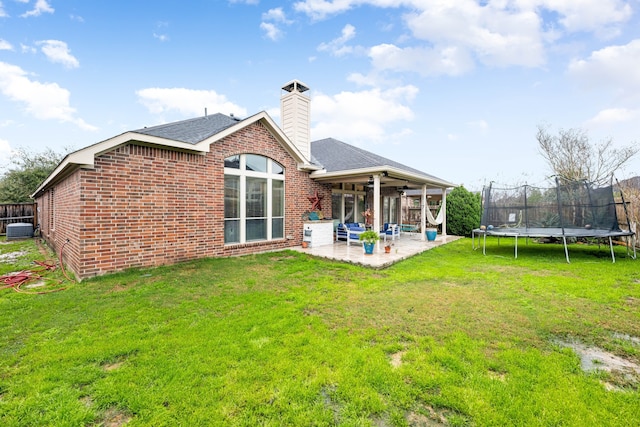 rear view of property with a patio, a trampoline, central AC, and brick siding