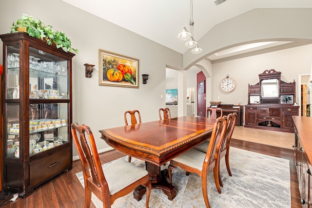 dining room with wood finished floors, visible vents, vaulted ceiling, and arched walkways