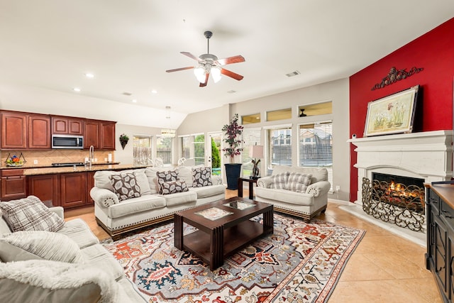 living area featuring a warm lit fireplace, light tile patterned floors, vaulted ceiling, visible vents, and a ceiling fan